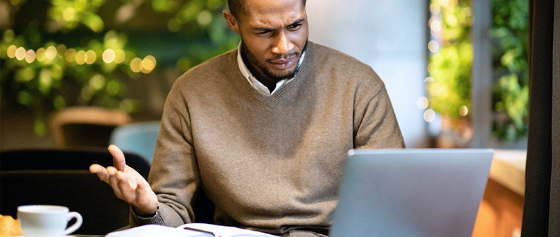 Confused man staring at laptop